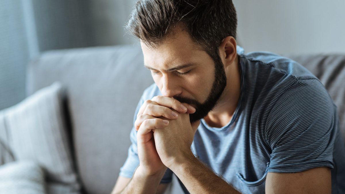 sad, tired man looking down at his hands